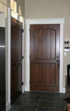 an entry way with a black refrigerator and brown door