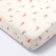 an image of a baby crib sheet with dinosaurs on the top and leaves on the bottom