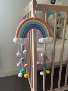 a crib with a rainbow mobile hanging from it's side