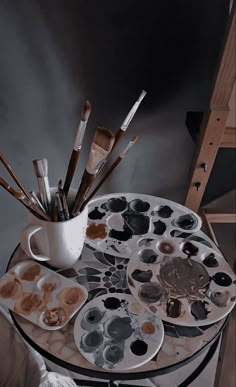 an artist's easel with paint brushes and palettes sitting on top of it