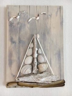 a sailboat made out of driftwood and sea shells on a white wooden background