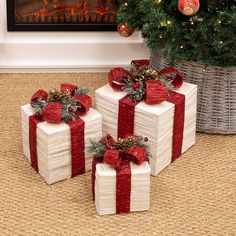 three wrapped presents sitting in front of a christmas tree