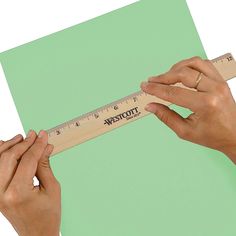 two hands are holding a tape measure on a green and white background with black numbers