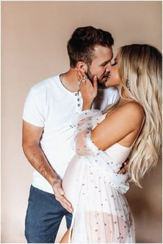 a man and woman kissing each other in front of a wall