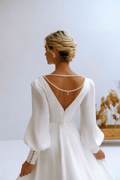 a woman in a white dress with pearls on her back