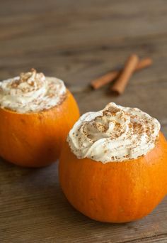 two oranges with whipped cream on them sitting on a table next to cinnamon sticks