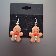 a pair of gingerbread man earrings on a black card board with the box behind it