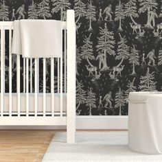 a white crib in front of a black and white wallpaper with animals on it