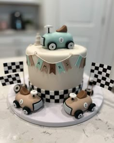 a cake decorated with cars and flags on top of a white tablecloth covered counter