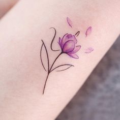 a purple flower tattoo on the arm with water droplets coming off it's petals