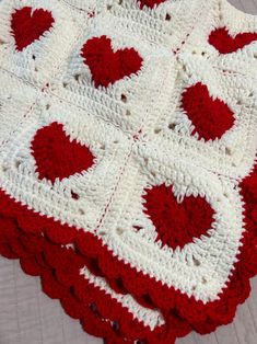 a red and white crocheted blanket on top of a bed