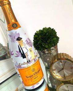 a bottle of champagne sitting on top of a table next to a clock and plant