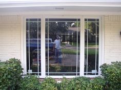 a man standing in front of a window with glass panes on the side of it