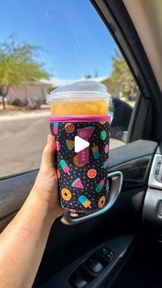 a person holding up a cup in their car