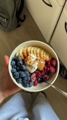 a person holding a bowl of fruit and yogurt