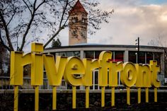 a sign that says riverfront in front of a building with a clock tower behind it