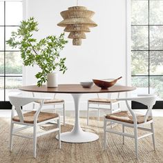 a dining room table with chairs and a plant in the center, next to a window