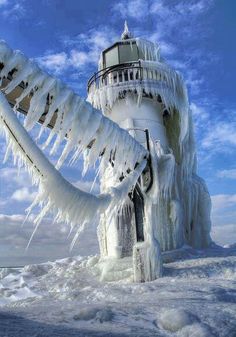 a lighthouse covered in ice and icicles under a blue sky