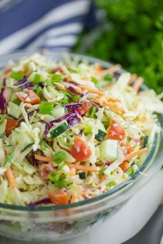 a glass bowl filled with coleslaw, carrots and celery on top of a table