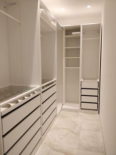 an empty walk - in closet with white cabinets and drawers