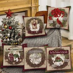 four christmas pillows on the floor next to a christmas tree