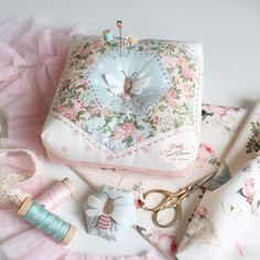 several sewing supplies are laid out on a white surface with pink ruffles around them