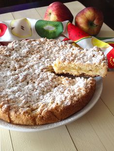 a cake on a plate with some apples in the background