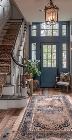 a blue door and some stairs in a house with a rug on the floor next to it