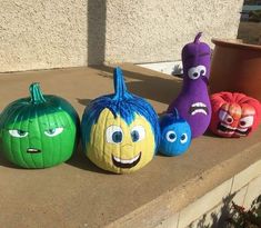 three pumpkins with faces painted on them sitting next to each other in front of a building