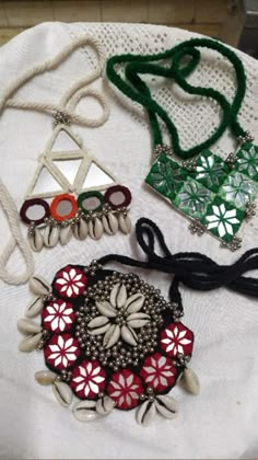 four different necklaces are laying on a white tablecloth with beads and chains hanging from them