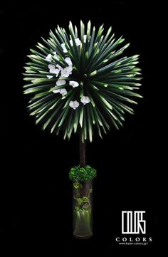 a vase filled with white flowers on top of a black table next to a plant