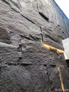 the side of a building that is made out of rocks and has lights on it