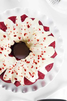 a red velvet cake with white frosting and sprinkles on a plate