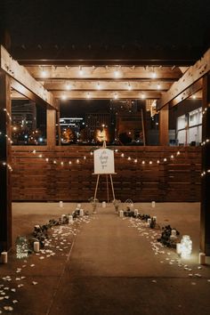 a wedding ceremony setup with candles and flowers on the ground in front of a wooden wall