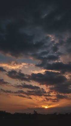 the sun is setting behind some dark clouds