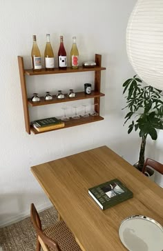 a wooden table topped with bottles of wine next to a shelf filled with books and drinks