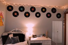 a bedroom decorated with vinyl record wall art and string lights above the bed, along with a white desk