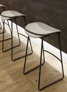 three stools sitting on top of a wooden floor in front of a brown wall