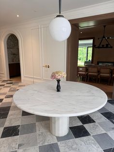 a white marble table with flowers on it in the middle of a checkered floor