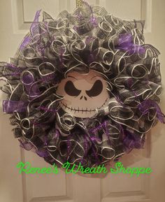 a halloween wreath with a skeleton face on the front door and purple ribbon around it