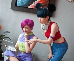 two women in colorful outfits are looking at a laptop