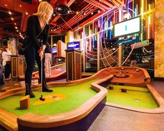 a woman is playing mini golf at the miniature golf course in an indoor setting with people watching