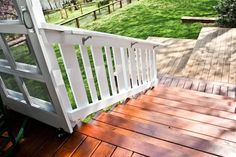 a wooden deck with white railing and green grass