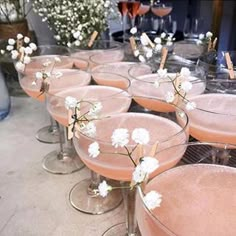 several glasses filled with different types of drinks and garnished with small white flowers