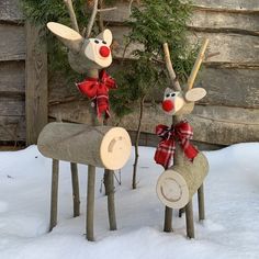 two wooden reindeers with red noses and bows on their heads are standing in the snow