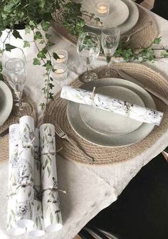 the table is set with place settings, napkins, and flowers in vases