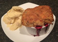 a white plate topped with an ice cream covered dessert next to potato chips and blueberry sauce