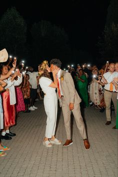 a bride and groom kissing in front of their guests with sparklers on their heads