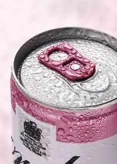 a can of soda with water droplets on the side and a pink object in the middle