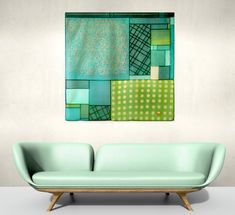 a green couch sitting in front of a painting on the wall